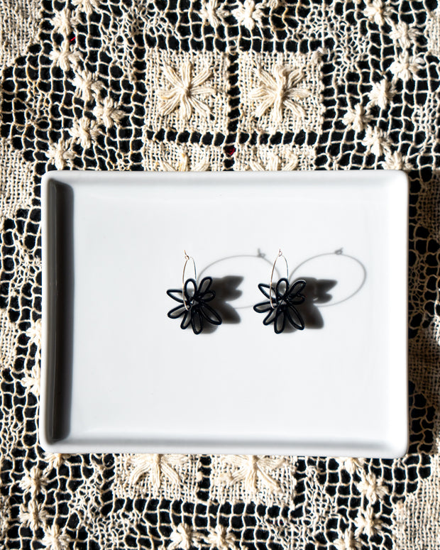 black flower hoop earrings on white tray