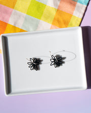 black flower hoop earrings on white tray