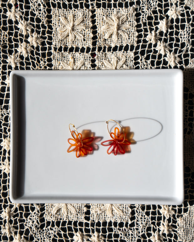 red orange flower gold hoop earrings on white tray 