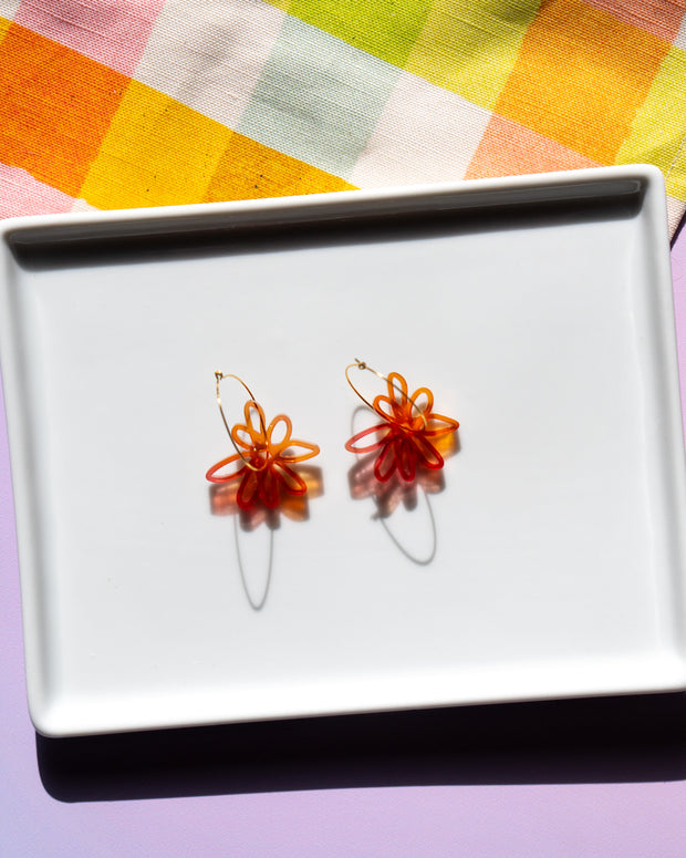 red orange flower hoop earrings on white tray