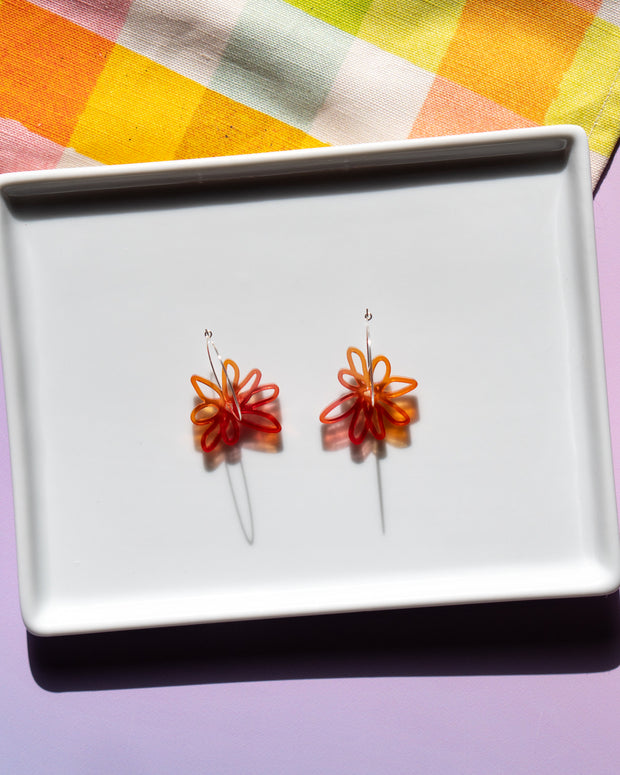 red orange flower hoop earrings  on white tray