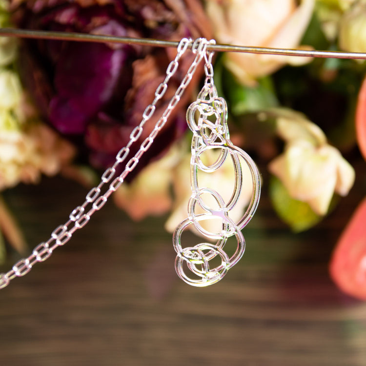 Iridescent pendant necklace over multicolored background