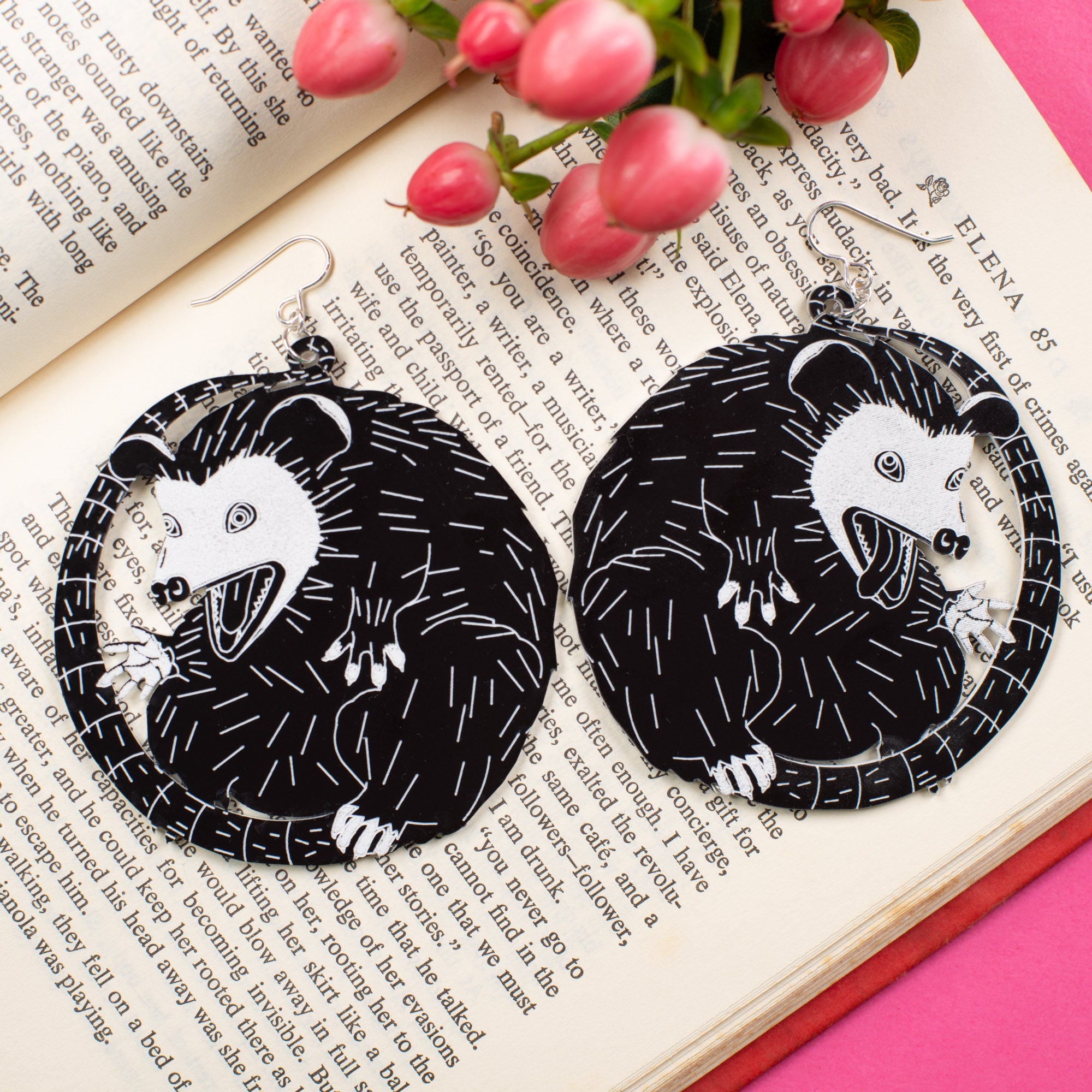 Large black possum earrings displayed on top of an open book