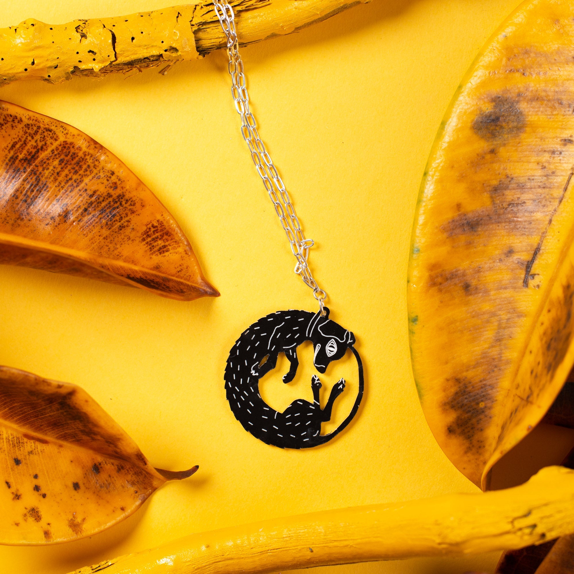 Black and white dog pendant necklace on yellow backdrop.