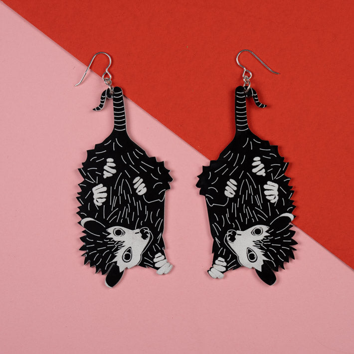 Large baby possum earrings over pink and red background