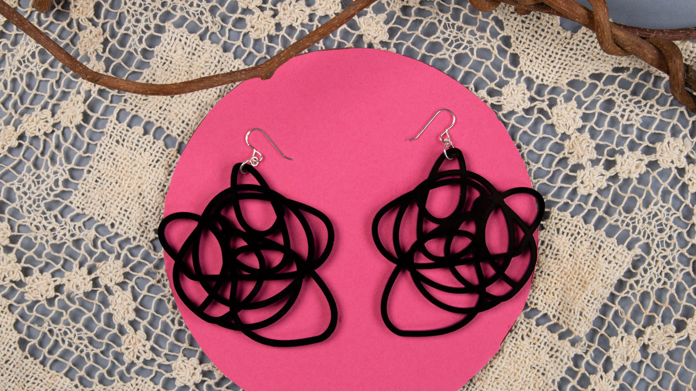Lightweight black grande earrings over pink and lace background