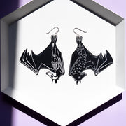 large black skeleton earrings on white tray