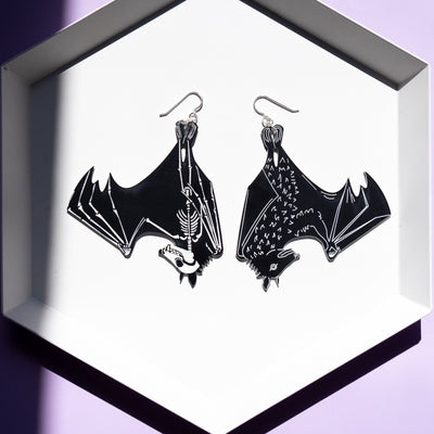 large black skeleton earrings on white tray