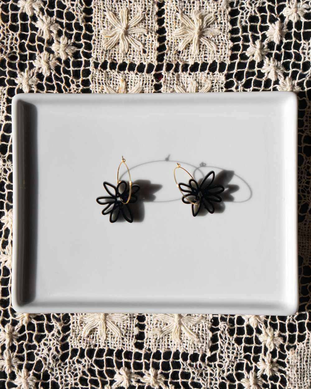 black flower gold hoop earrings on white tray
