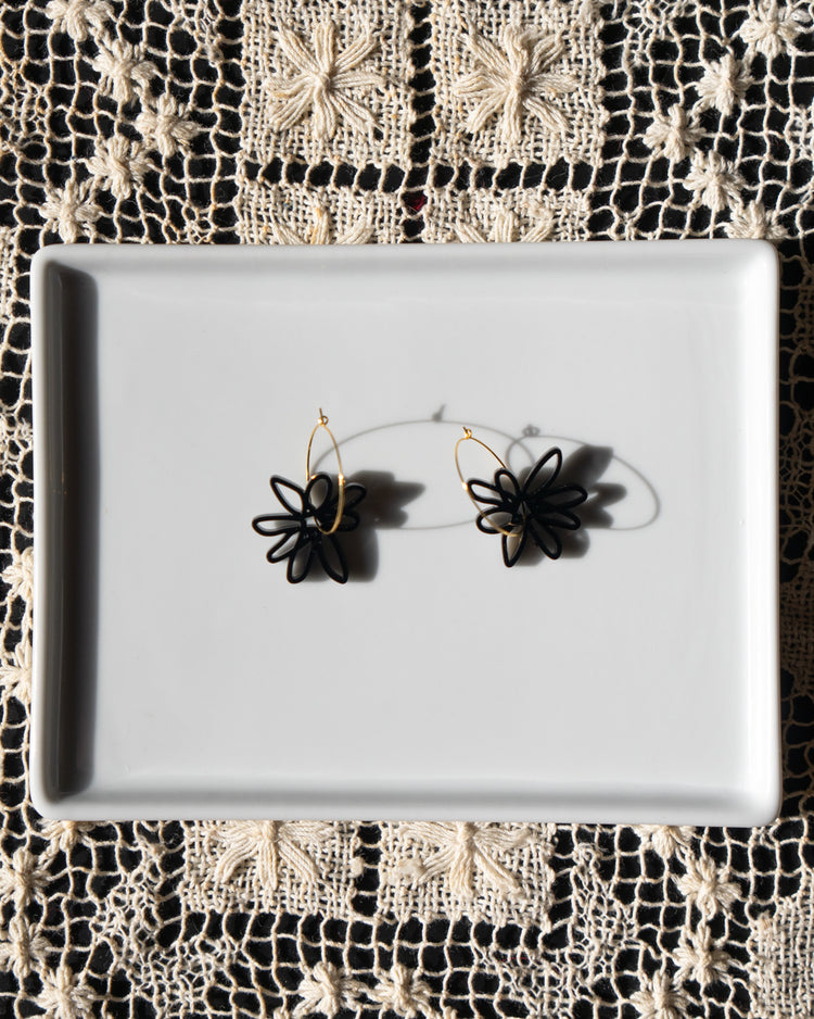 black flower gold hoop earrings on white tray