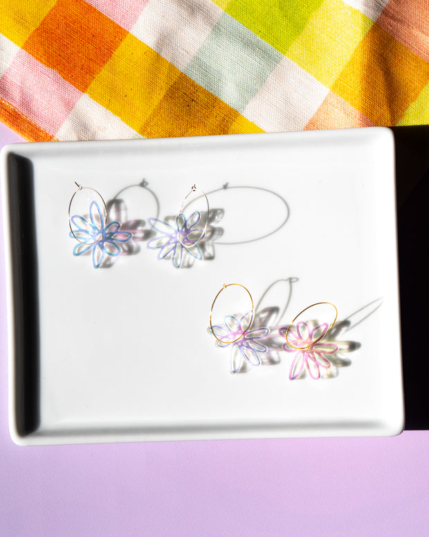 Iridescent flower hoops in silver and gold on white tray