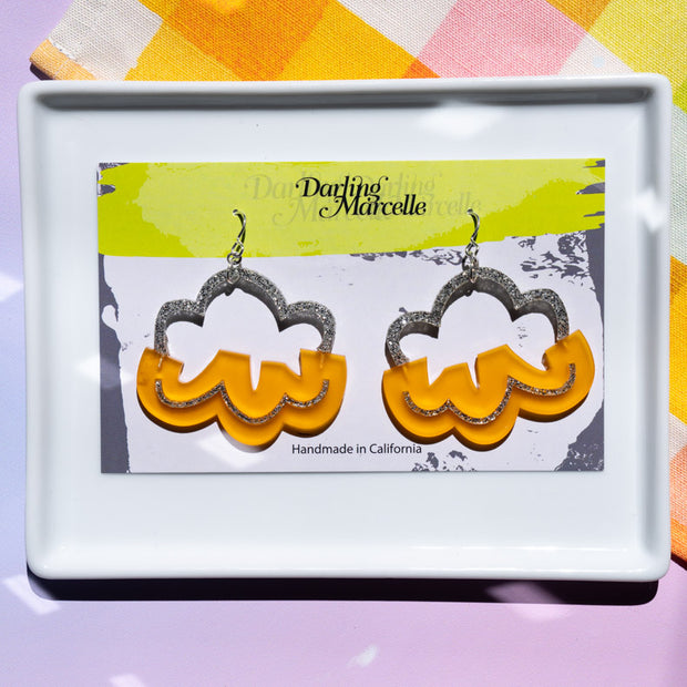 Orange and silver cloud earrings on an earring card atop a white tray
