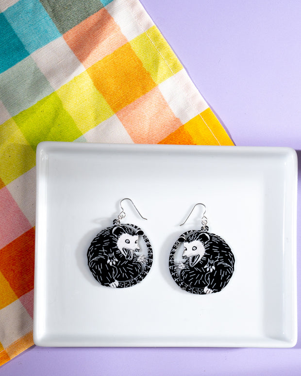 small black and white possum earrings on white tray on rainbow cloth