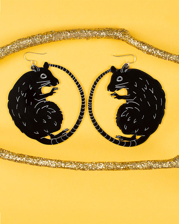 large black and white rat earrings over yellow background