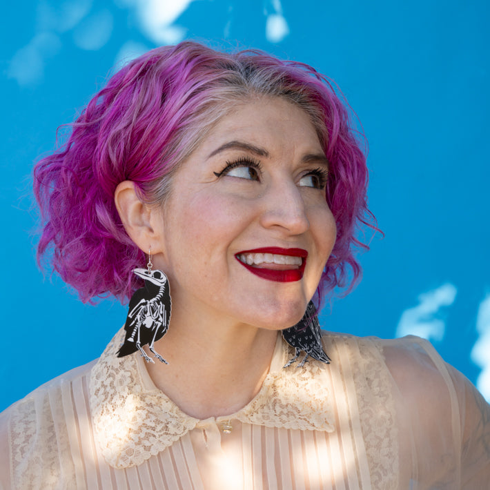 Model wearing large raven skeleton earrings