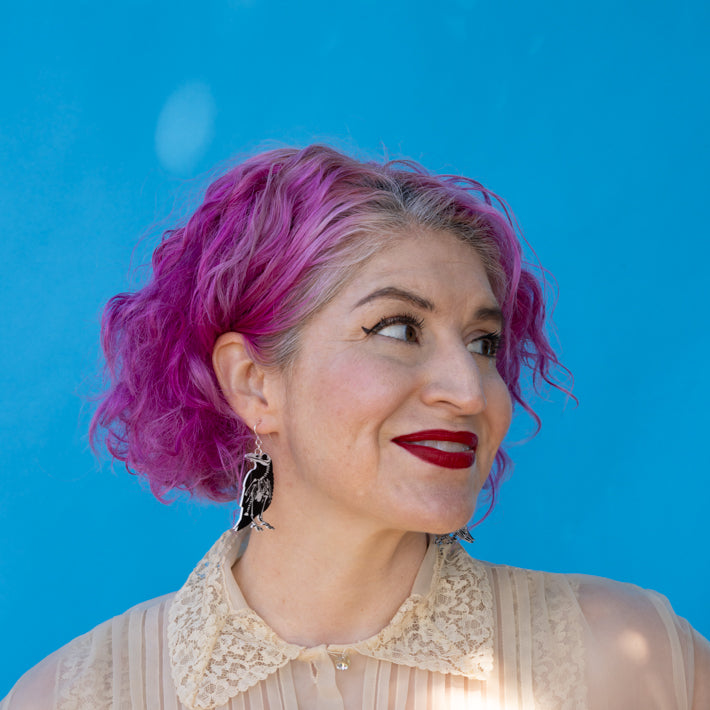 Model wearing small raven skeleton earrings