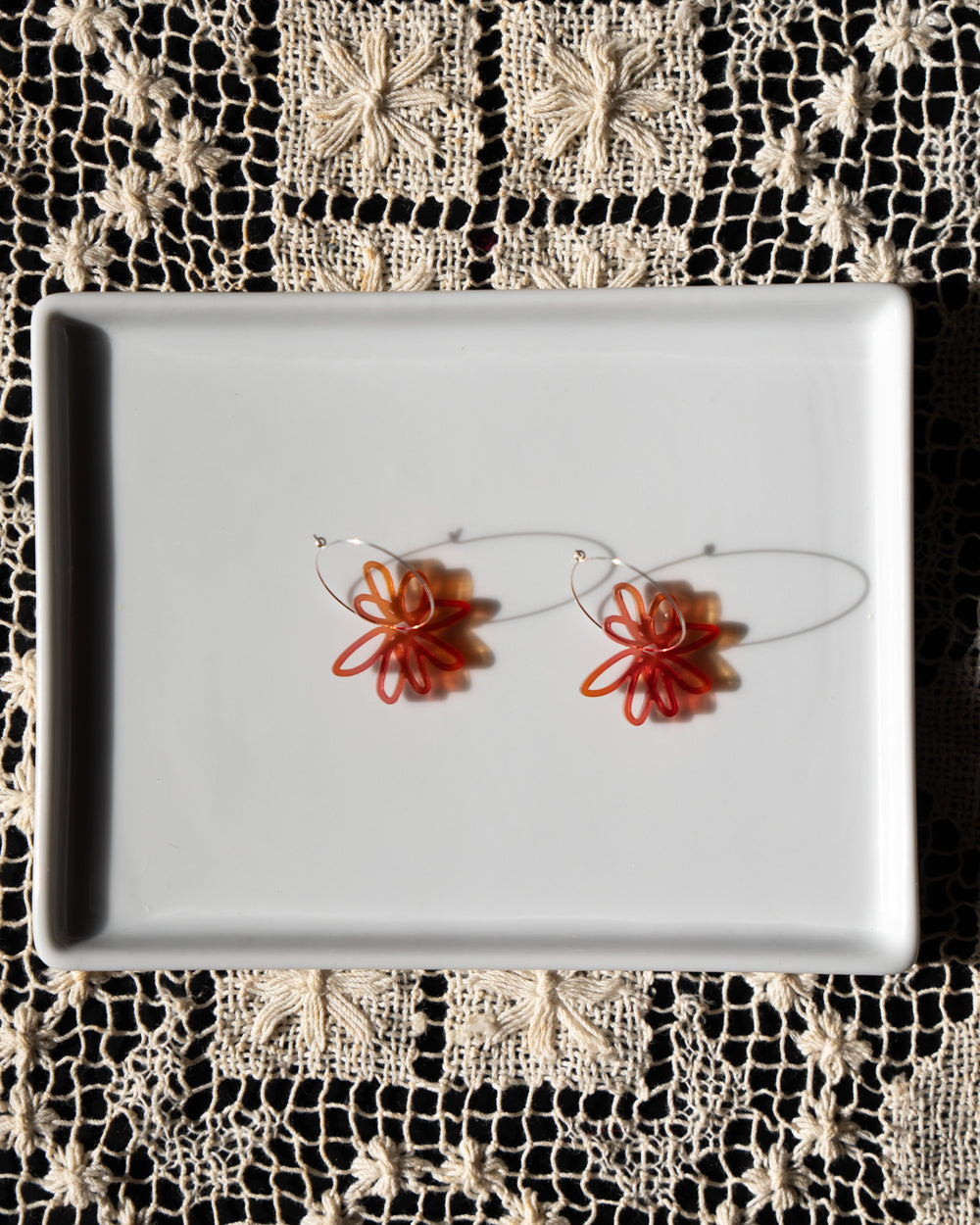 red orange flower hoop earrings  on white tray