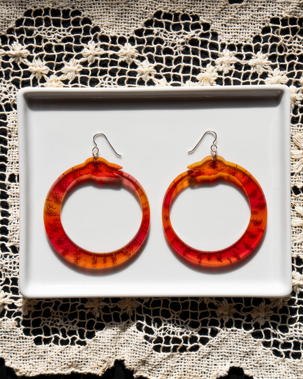 large red ouroboros earrings on white tray 