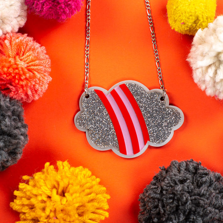 Silver lining rainbow cloud necklace shown over colorful background