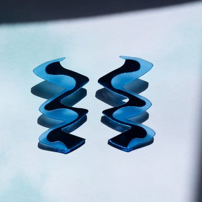 Zigzag blue acrylic Earrings shown over light blue background