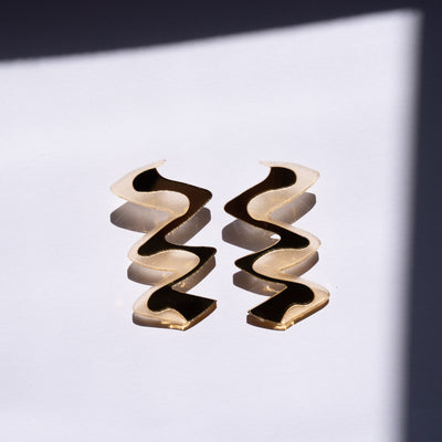 Zigzag gold acrylic earrings shown near window