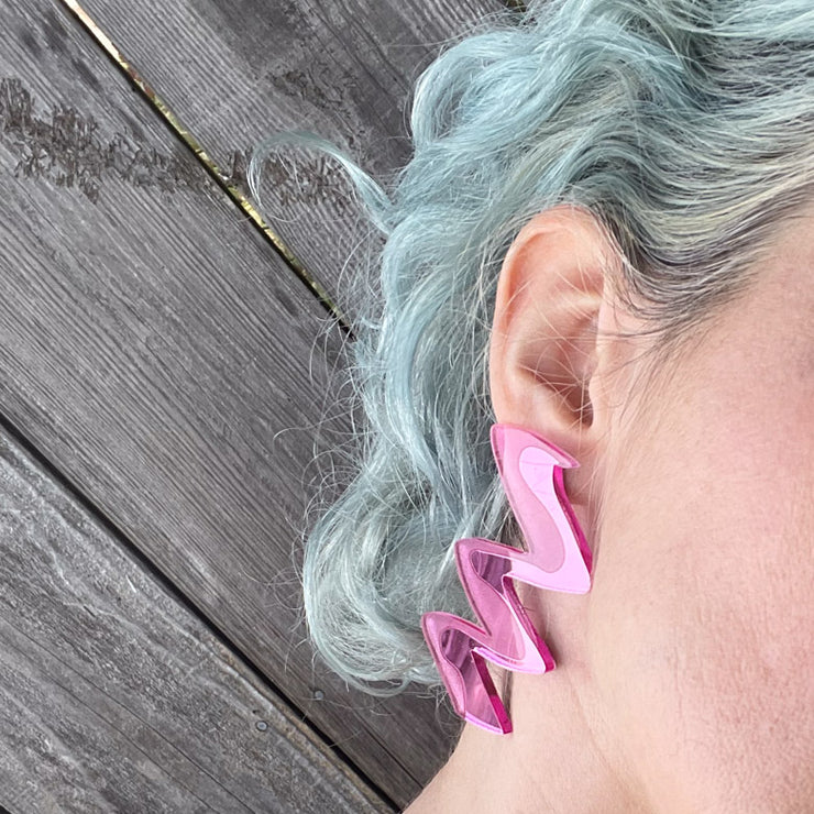 Detail of pink acrylic earrings on model