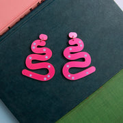 hot pink abstract acrylic earrings styled on blue book