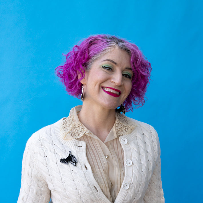 bat pin worn by model with pink hair in front of blue background