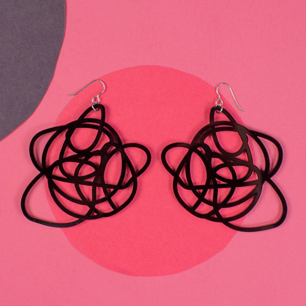 black graffiti statement earrings over pink and black background