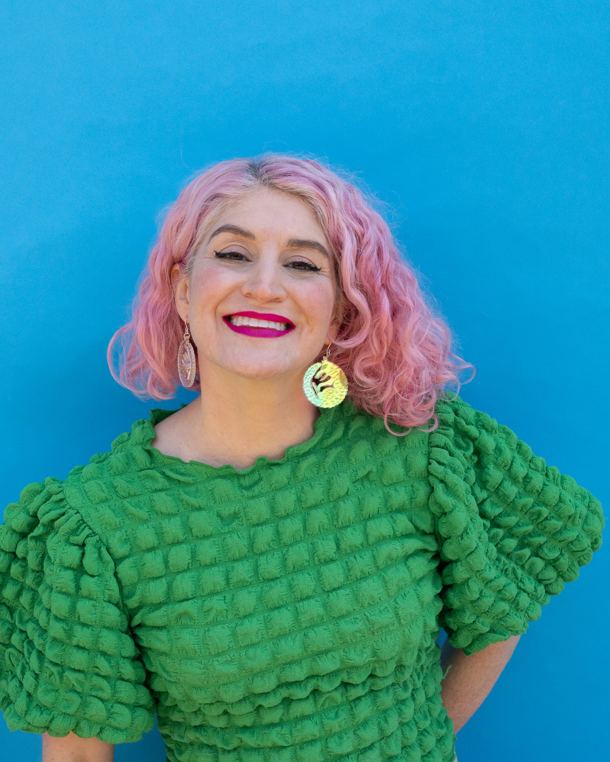 Small iridescent wolf earrings on model with pink hair