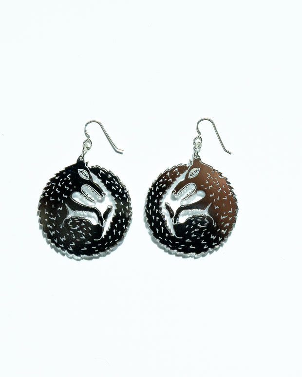 Small mirrored wolf earrings over white