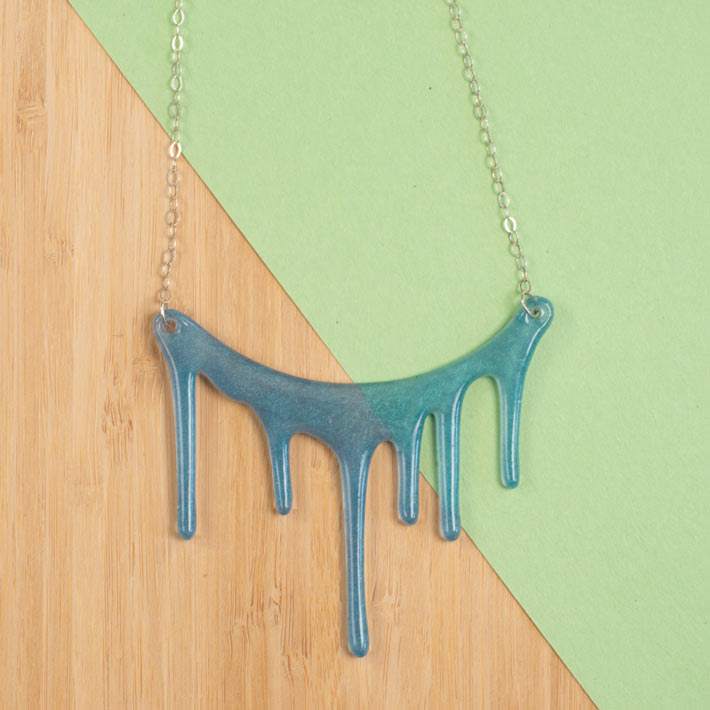 translucent blue necklace over green and wood background