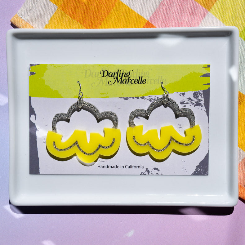 Silver and yellow cloud earrings on earring card atop white tray