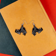 black bat earrings on top of books