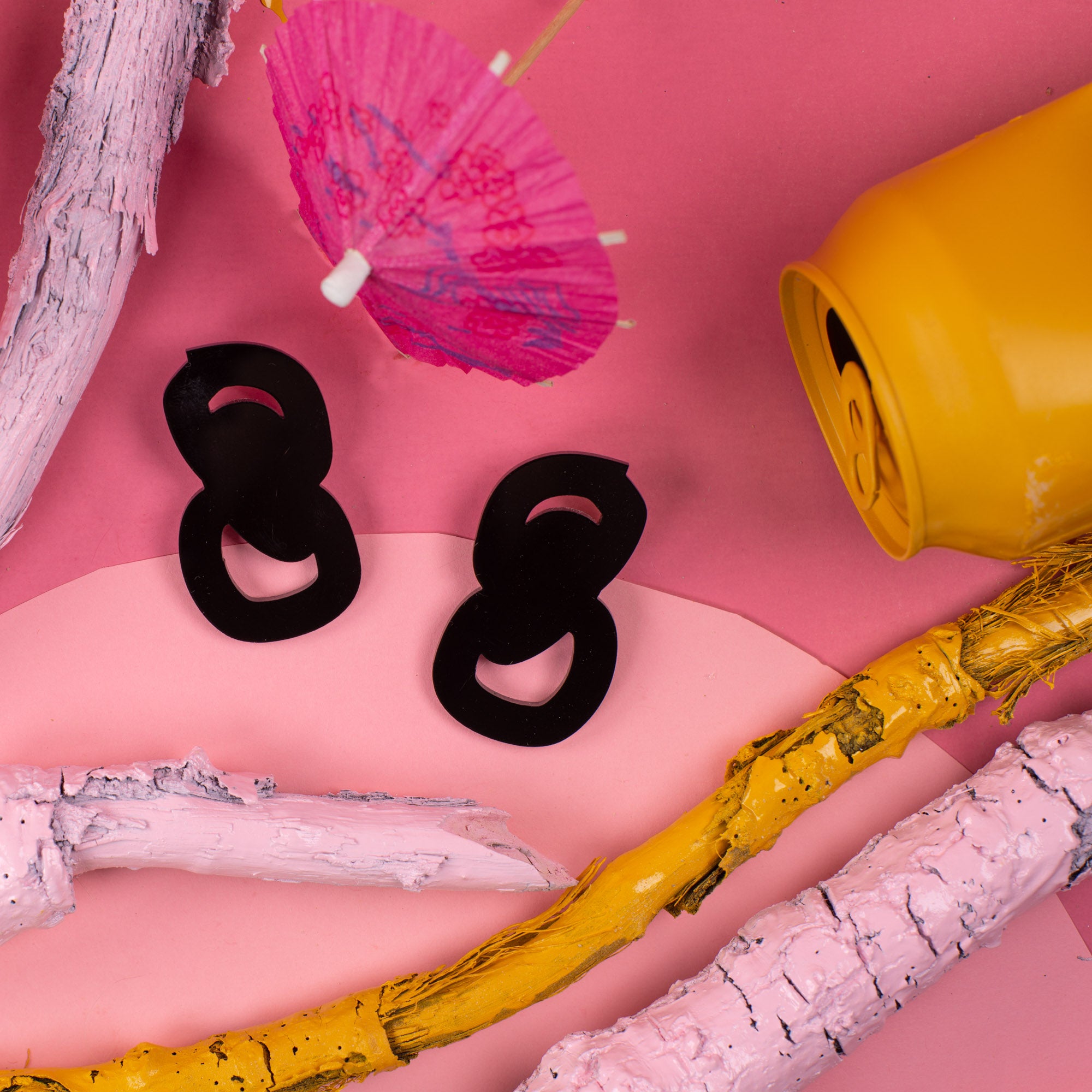 black statement stud earrings on pink background with props