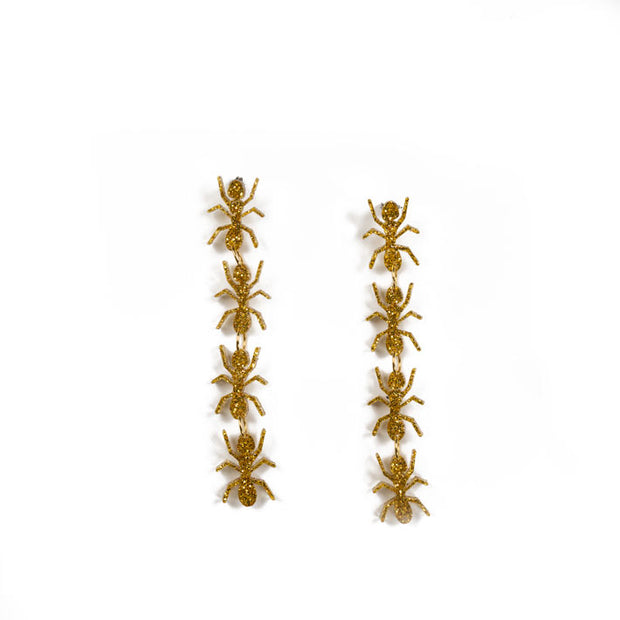 gold ant earrings over white background