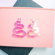 iridescent squiggle earrings on pink book