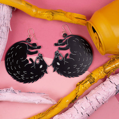 large black boar earrings styled over pink background