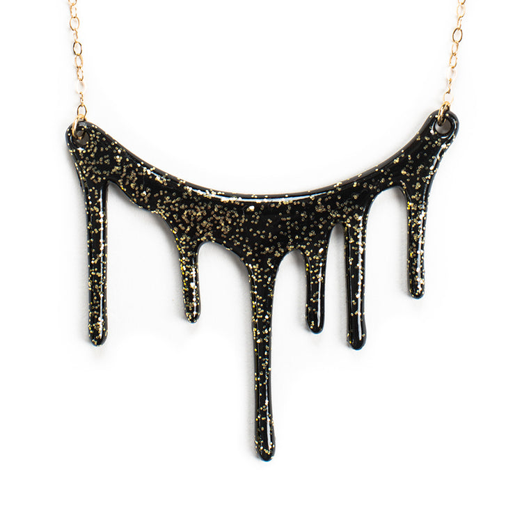 black and gold glitter necklace over white