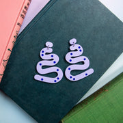 Pastel lilac squiggle earrings shown on top of book