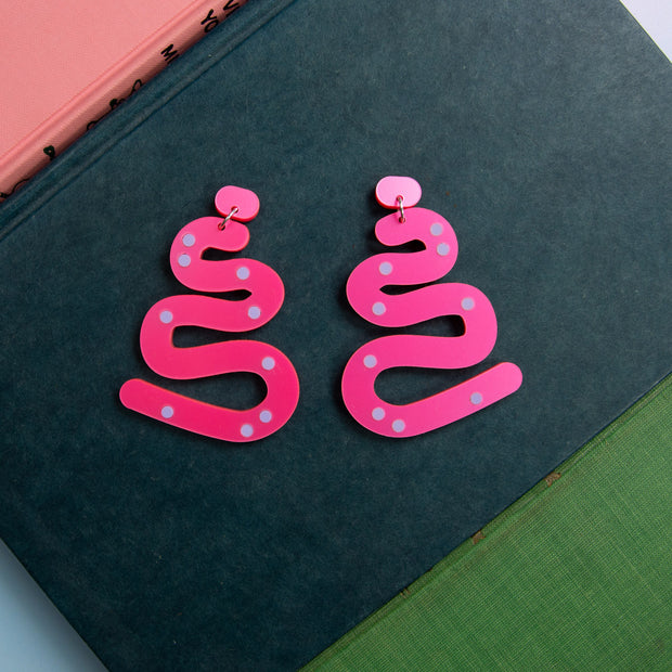 Hot Pink Squiggle Earrings shown on blue book.