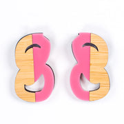 Pink and wood statement stud earrings over white