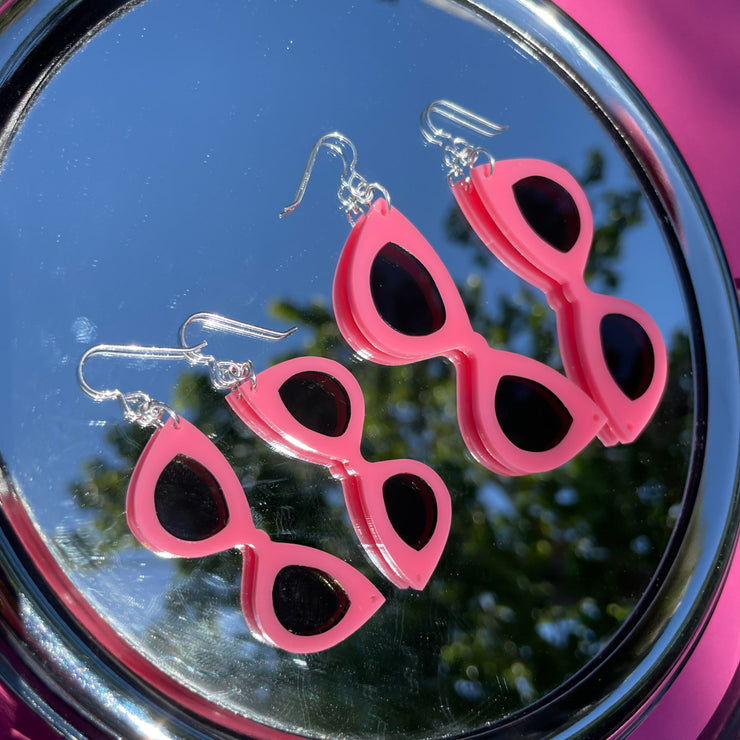 large and small pink sunglass earrings shown on mirror