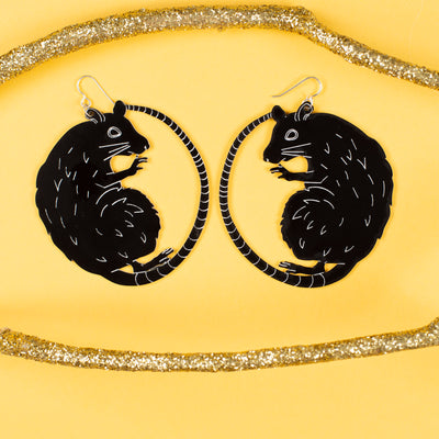 Large black rat earrings on yellow background