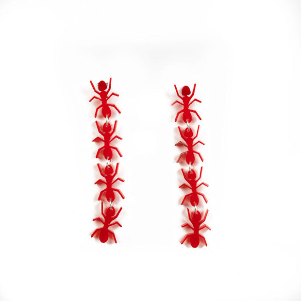 Red ant earrings over white background