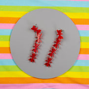 Red ant earrings on colorful background