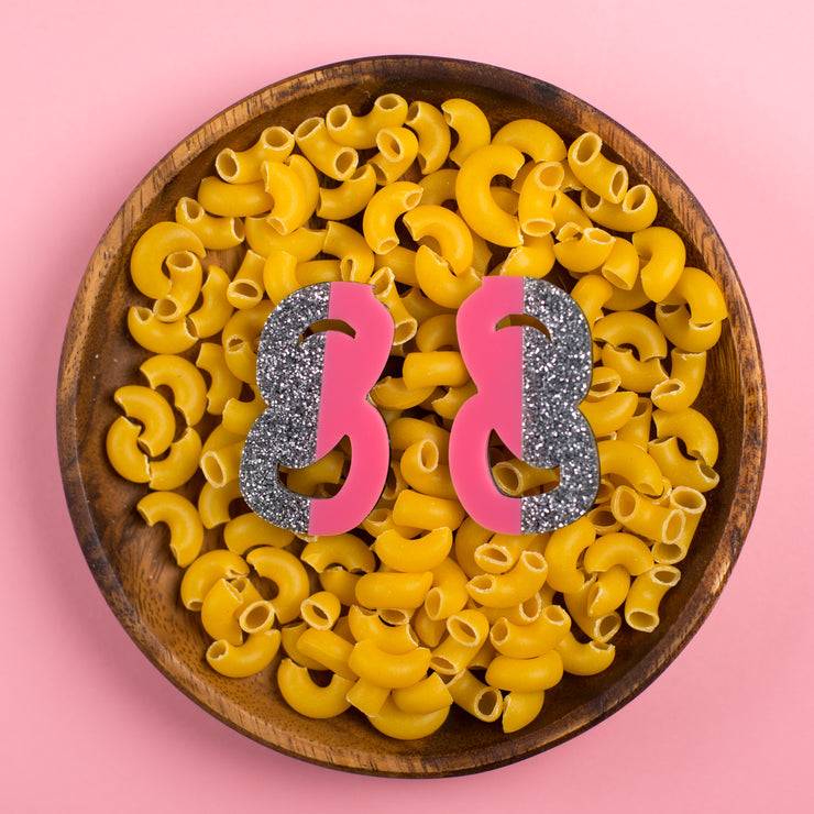silver and pink statement stud earrings in bowl of macaroni noodles