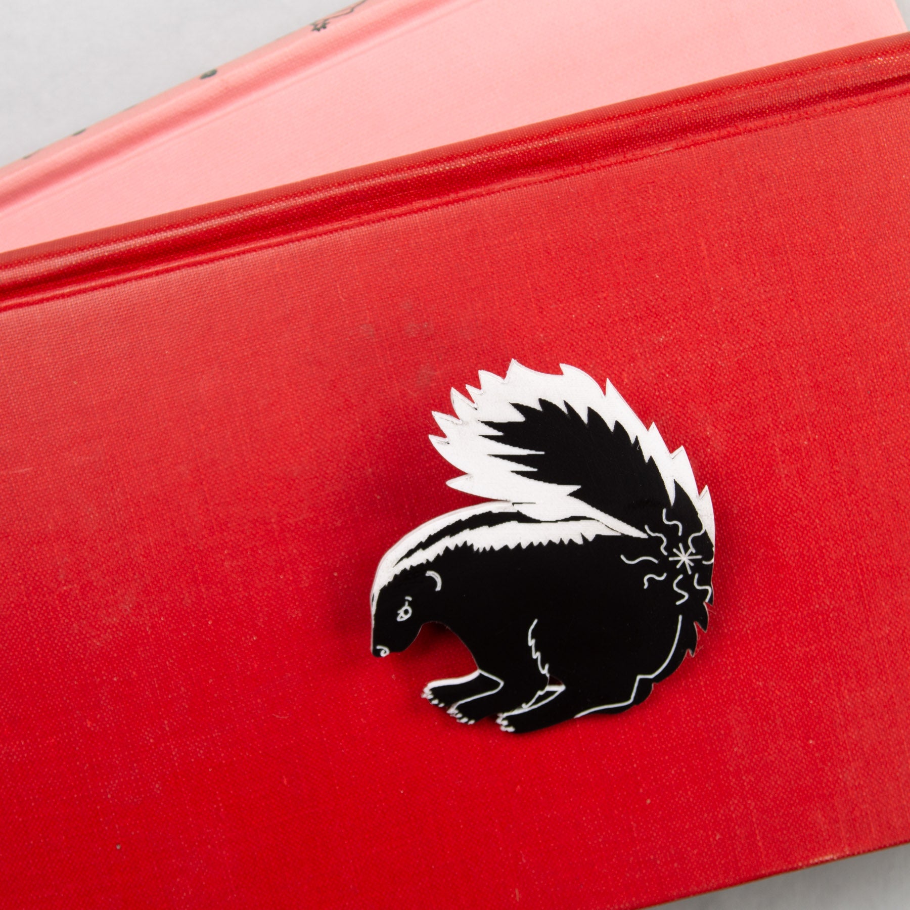 Skunk pin on red background