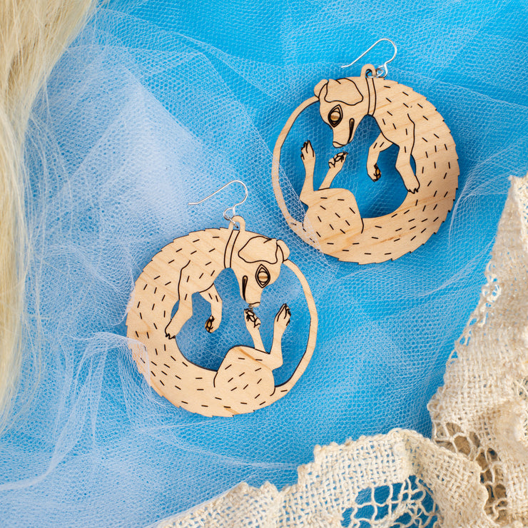 small wood dog earrings on blue background