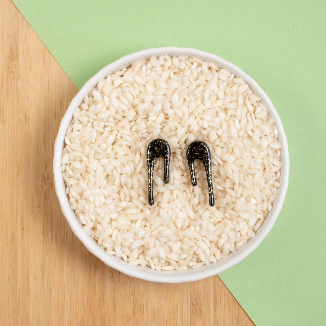 black and gold drop earrings styled in bowl of rice